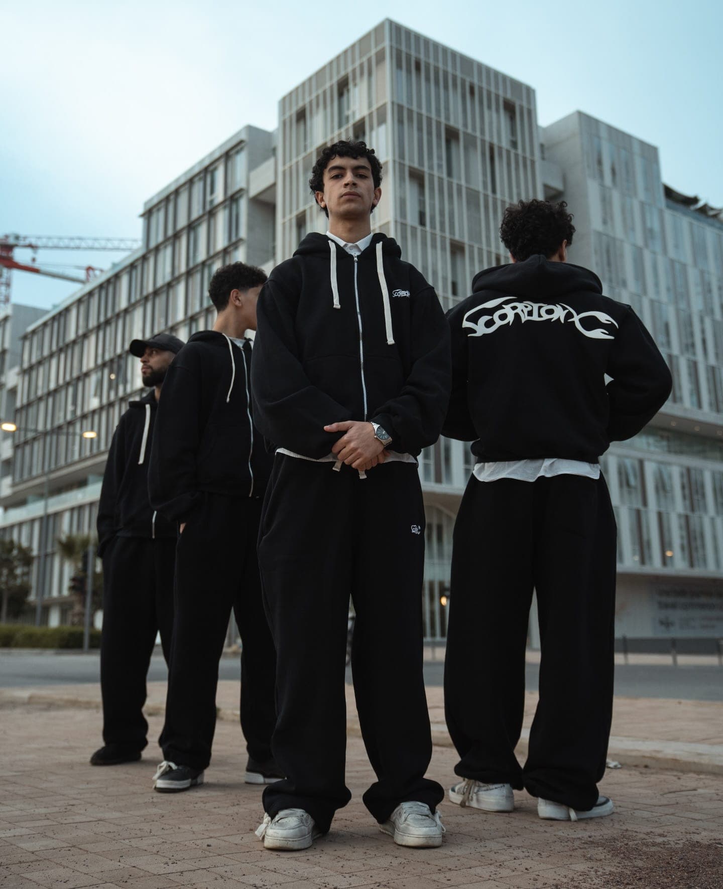 Five crew members in tracksuits, one showing the ScorpionX back print