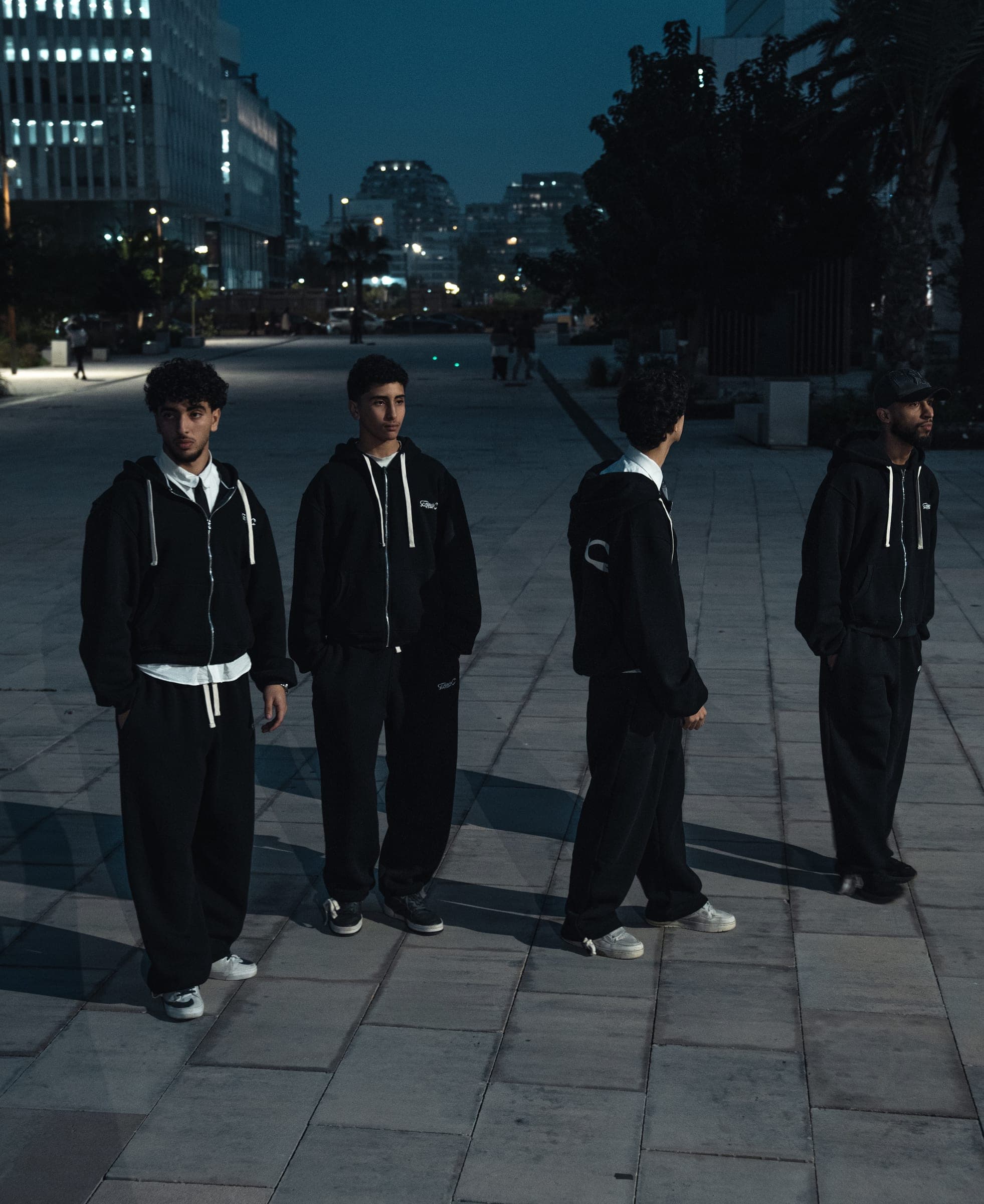 Four members of the ScorpionX crew at blue hour in matching zip-up hoodies and wide pants